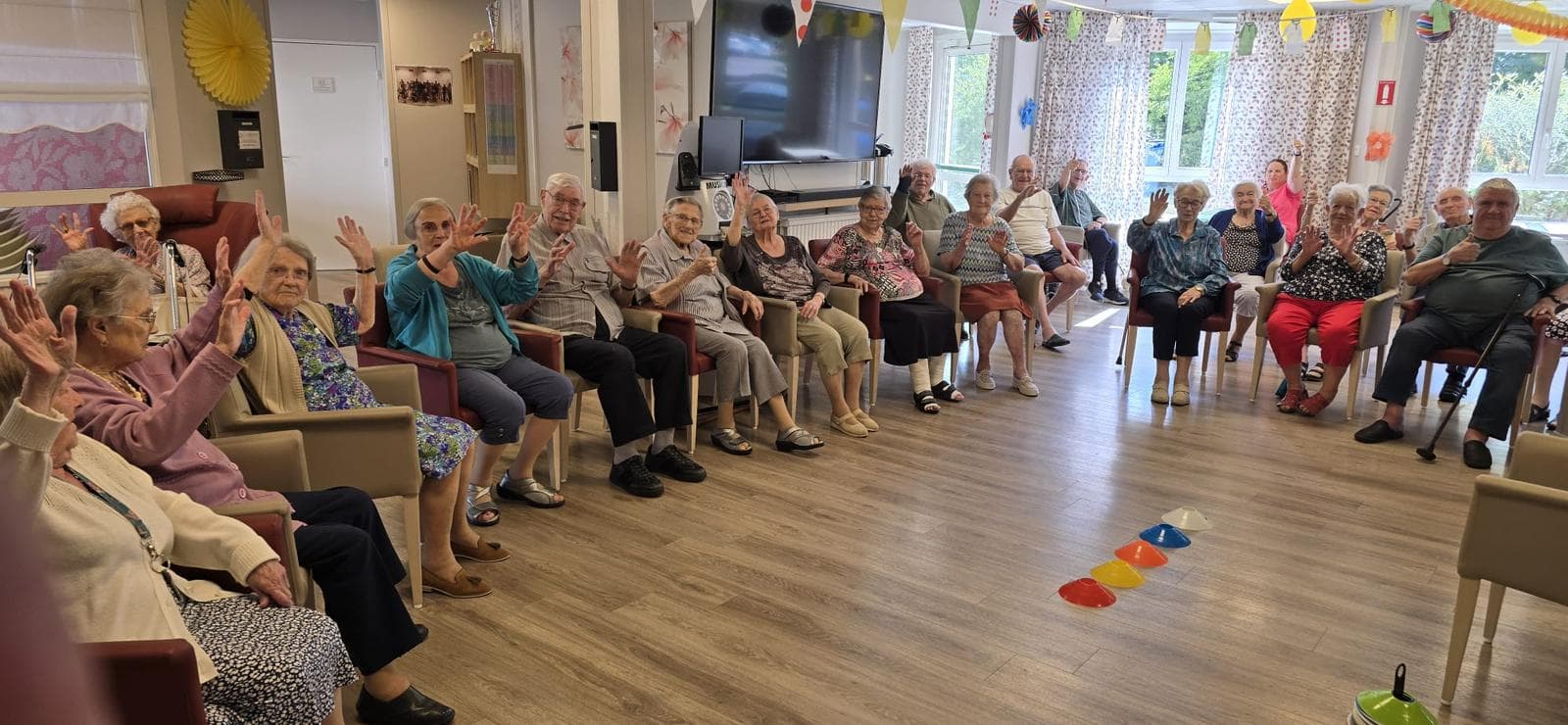 CREADIAZ® workshop: a group of seniors seated on chairs, hands raised in a guided movement